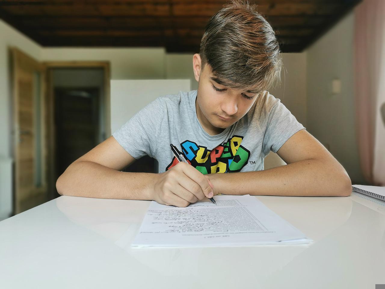 teen boy writing on paper