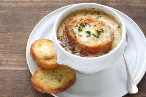 Bowl of French onion soup with French bread on the side