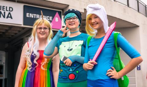 three teen girls dressed in colorful costumes