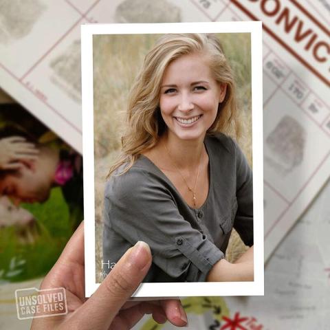 fingers holding photo of young, blonde woman smiling with case files in background