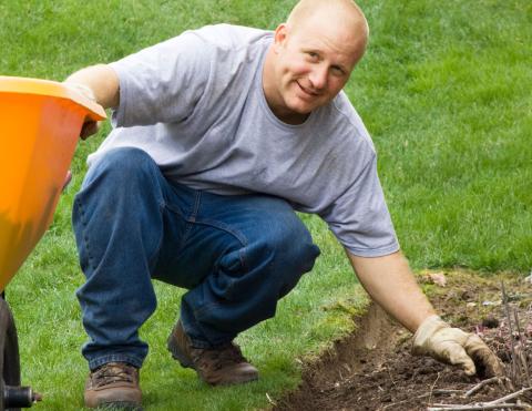 man kneeling down preparing garden space