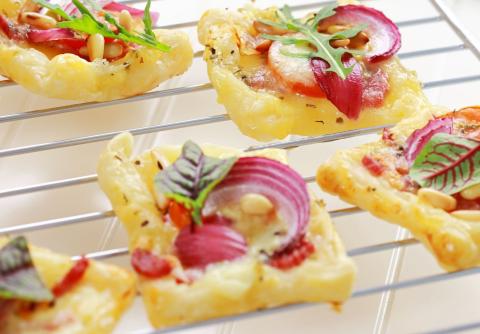 baked puffed pastry appetizers with red onions and greens on oven rack