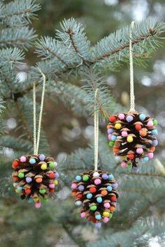 brown pine cone ornaments with colorful details hanging on green pine tree