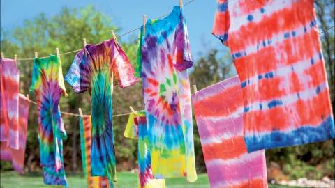 shirts that have been tie dyed hanging on a clothesline