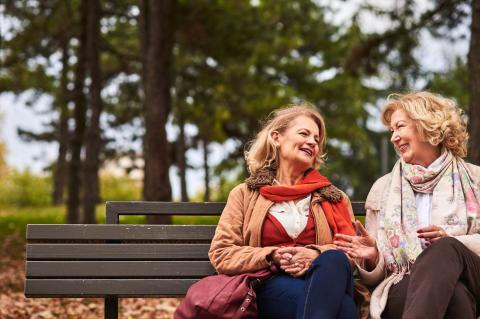 two women friends talking on a park bench