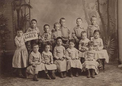 Native American children at Haskell Indian Boarding School circa 1880-1889, holding sign that says "Haskell Babies"