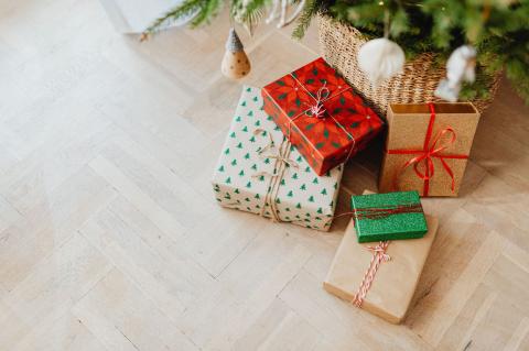Wrapped Christmas presents sitting next to a potted holiday plant