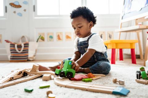 toddler playing with wooden blocks inside 