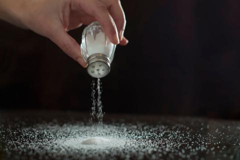 hand pouring salt from a salt shaker onto a surface