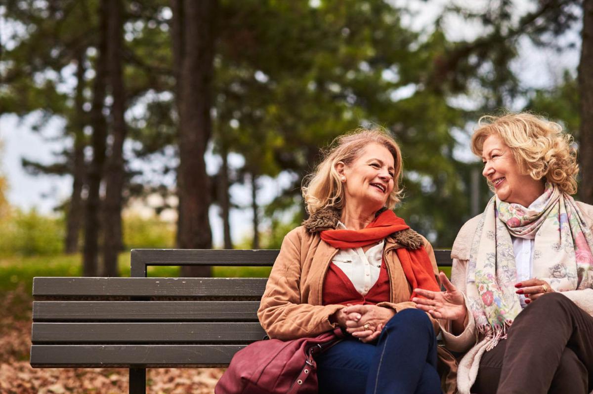 two women friends talking on a park bench