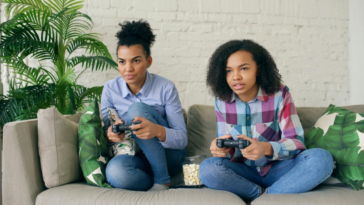 Two teens sitting on a couch playing video games